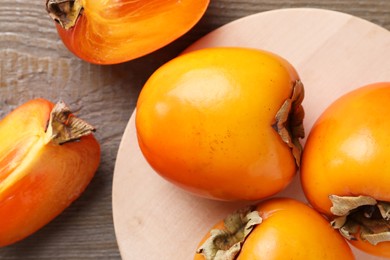 Photo of Whole and cut delicious ripe persimmons on wooden table, flat lay