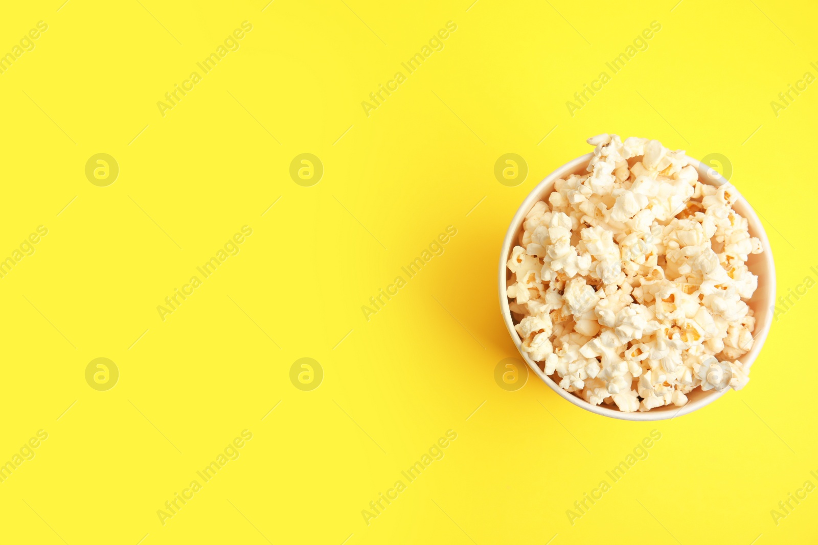 Photo of Tasty pop corn on yellow background, top view. Space for text