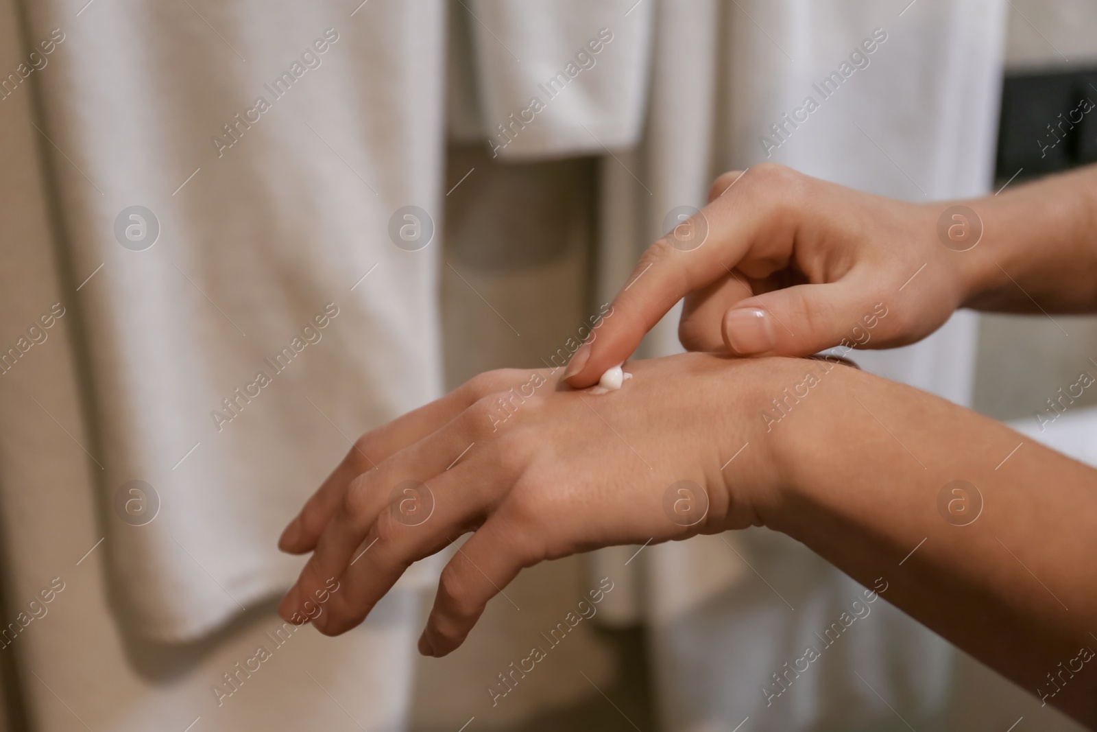 Photo of Woman applying hand cream in bathroom, closeup