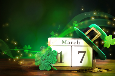 Image of Block calendar, hat and clover on wooden table. St. Patrick's Day celebration