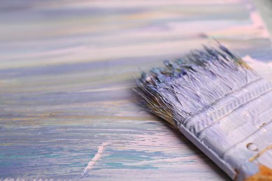 Photo of Strokes of colorful paints and brush on canvas, closeup