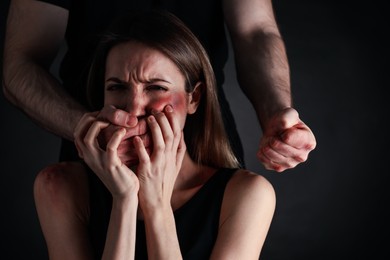 Man abusing scared woman on black background. Domestic violence