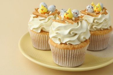 Tasty Easter cupcakes with vanilla cream on beige background, closeup