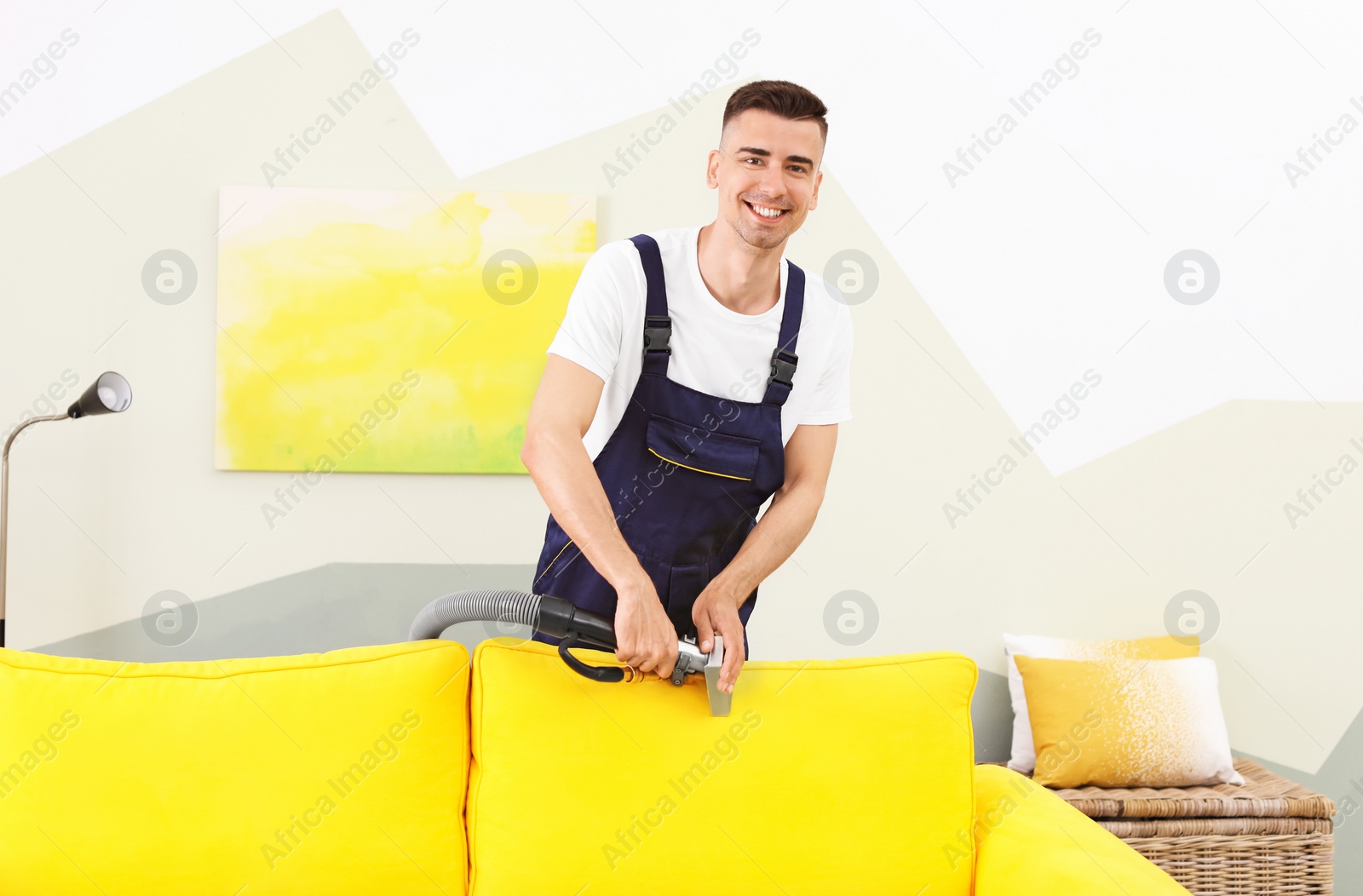 Photo of Dry cleaning worker removing dirt from sofa indoors