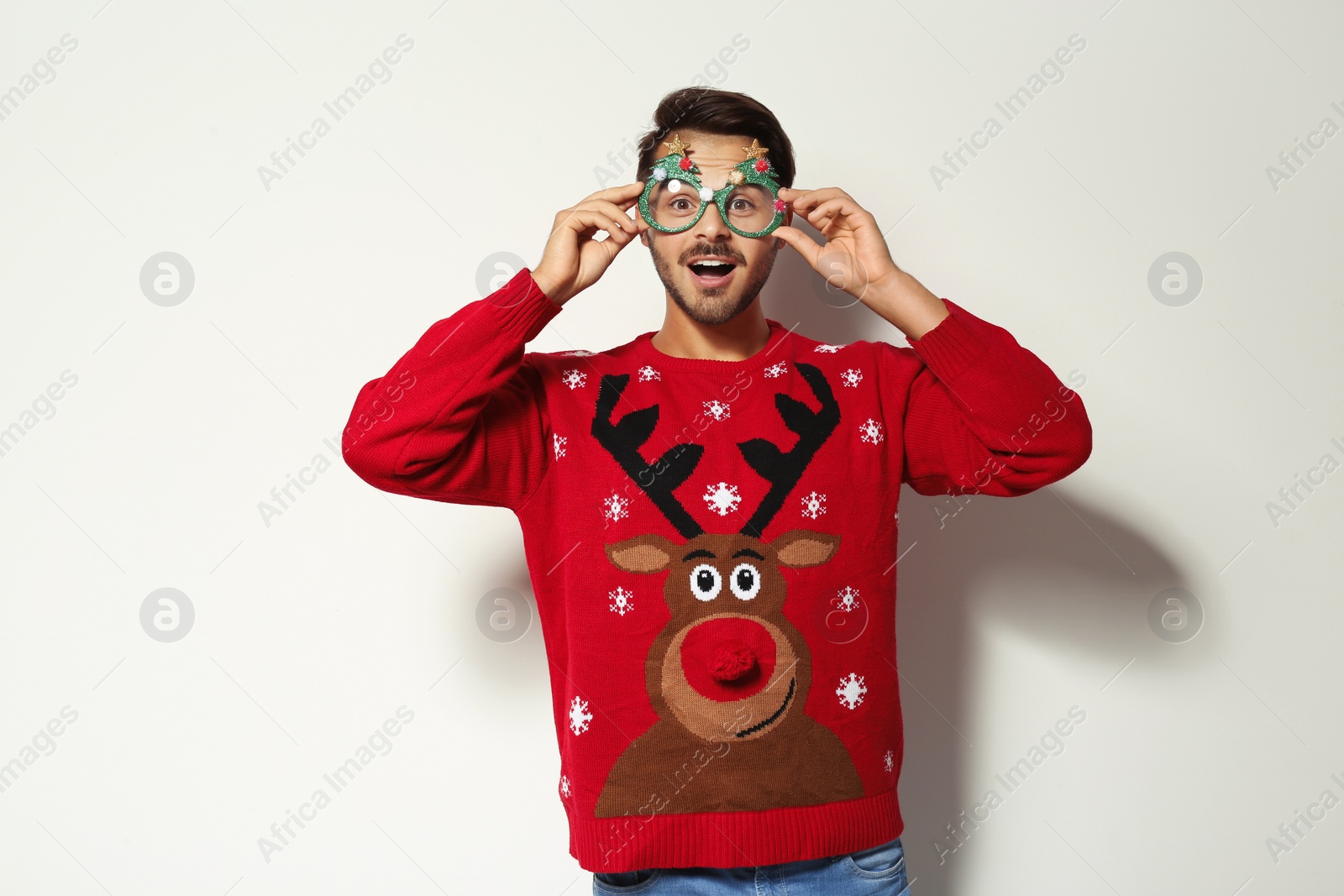 Photo of Young man in Christmas sweater with party glasses on white background