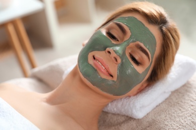 Beautiful woman with mask on face relaxing in spa salon