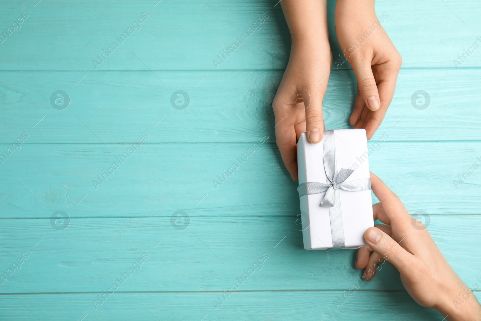 Photo of Daughter giving present to her dad at light blue wooden table, top view with space for text. Happy father's day