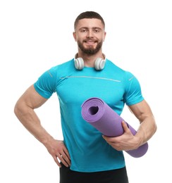 Handsome man with fitness mat and headphones on white background