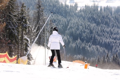 Photo of Woman skiing on snowy hill in mountains. Winter vacation