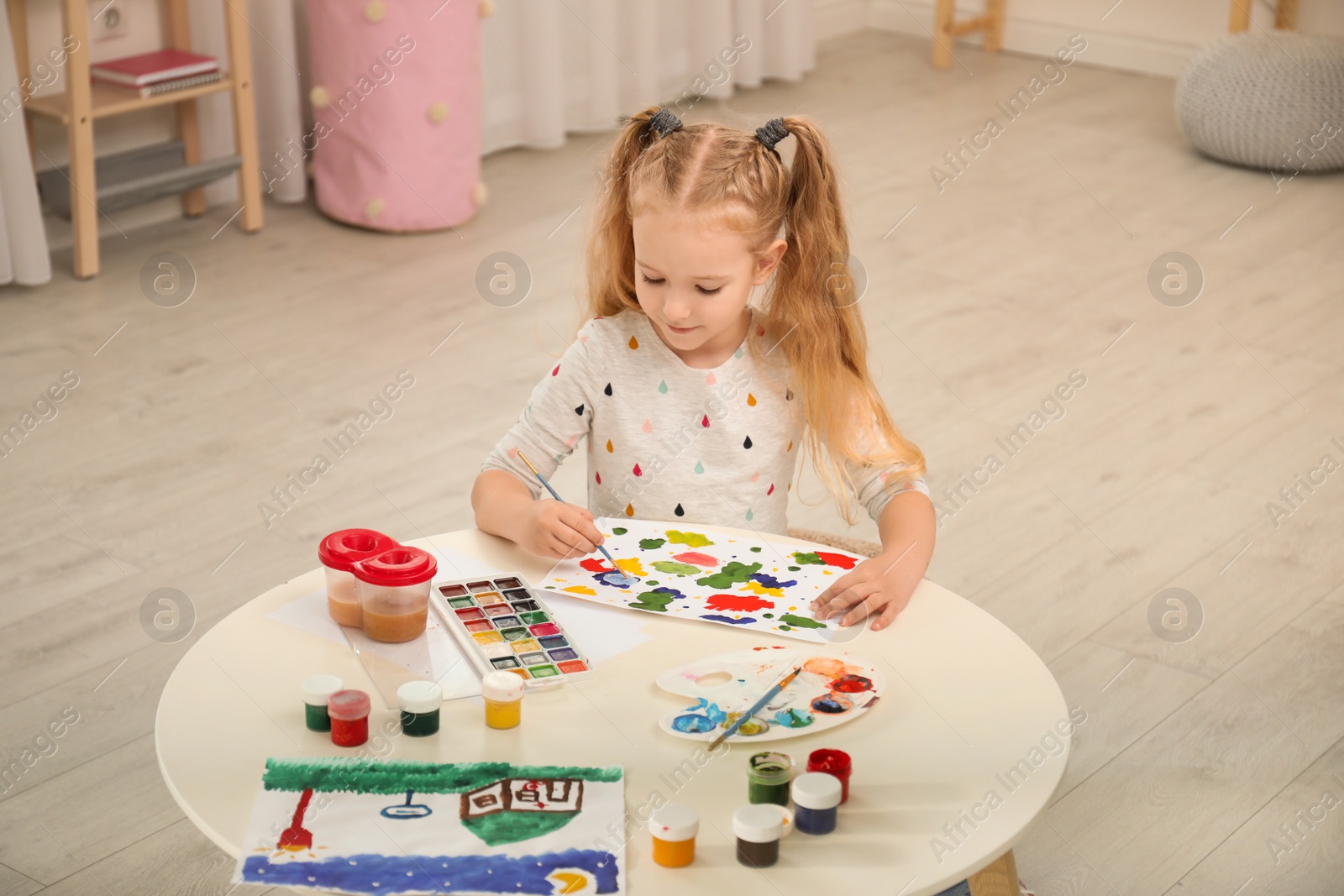 Photo of Cute little child painting at table in room