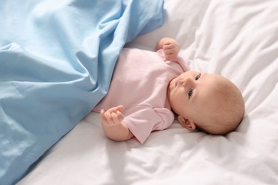 Photo of Cute little baby lying on white sheets