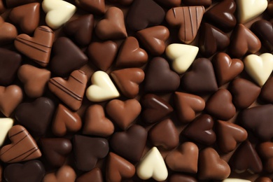 Beautiful heart shaped chocolate candies on brown background, flat lay