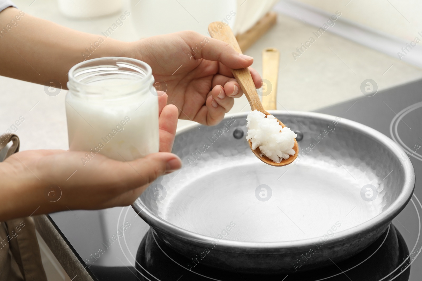 Photo of Woman cooking with coconut oil on induction stove, closeup