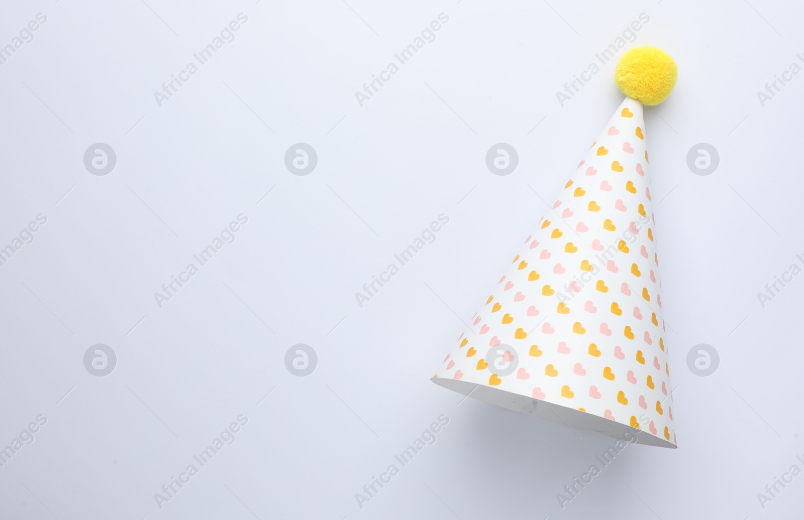 Photo of One party hat with hearts on light background, top view. Space for text