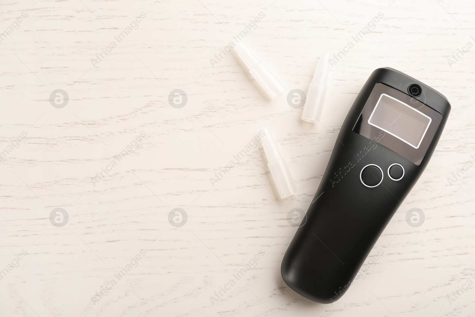 Photo of Modern breathalyzer with blank screen and mouthpieces on white wooden table, flat lay. Space for text