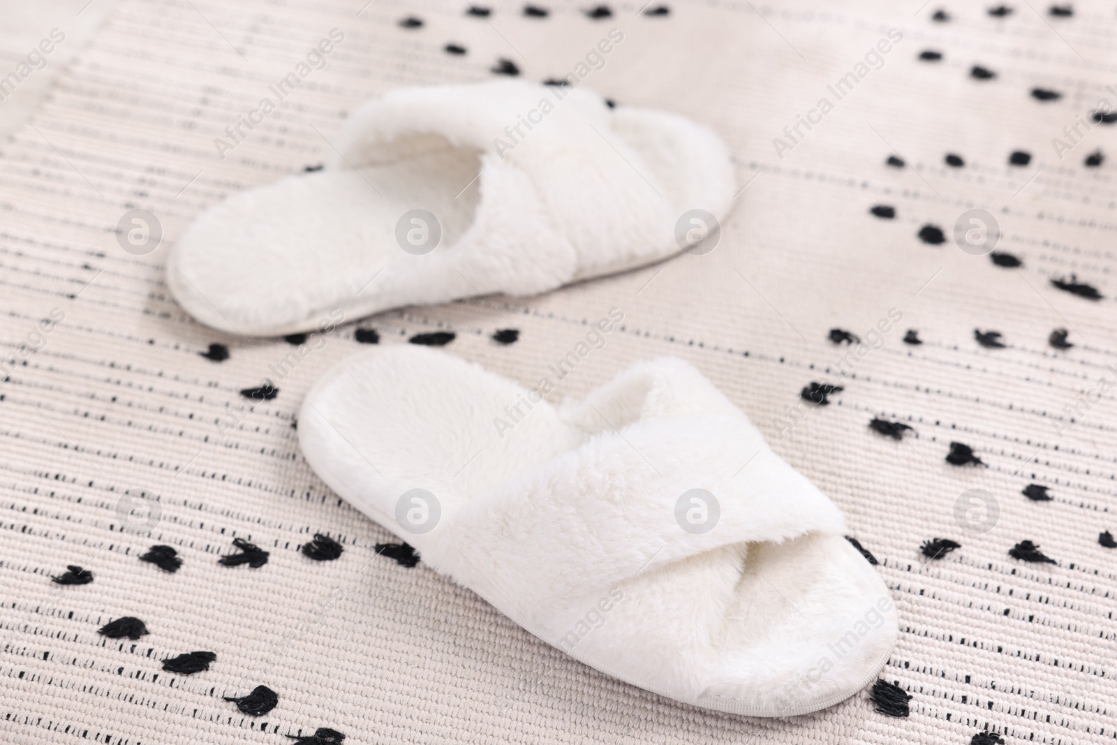 Photo of White soft slippers on carpet at home, closeup
