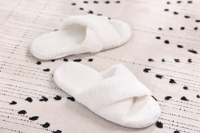 Photo of White soft slippers on carpet at home, closeup