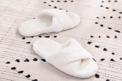 White soft slippers on carpet at home, closeup