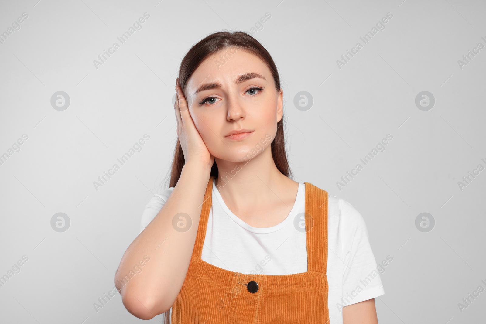 Photo of Young woman suffering from ear pain on light grey background