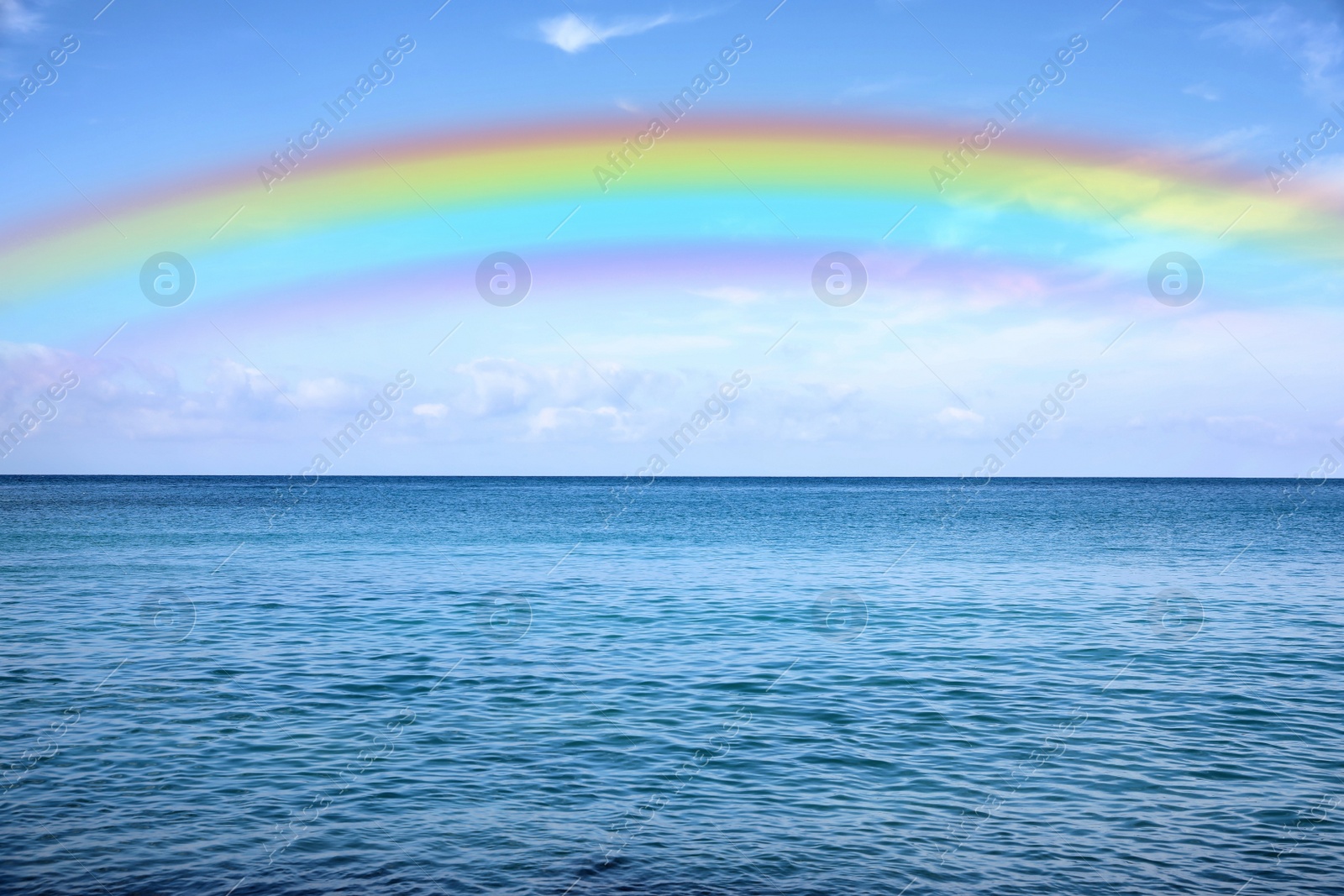 Image of Beautiful rainbow in blue sky over sea on sunny day