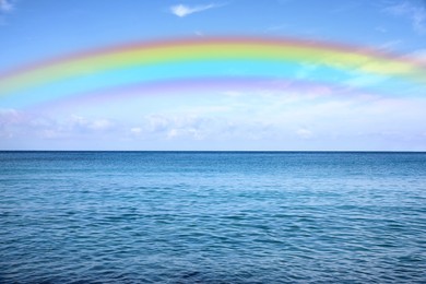 Image of Beautiful rainbow in blue sky over sea on sunny day