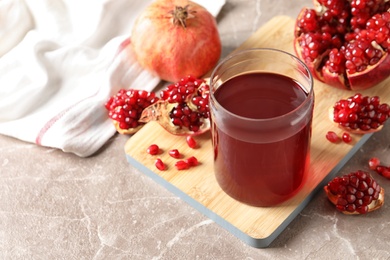 Photo of Composition with glass of fresh pomegranate juice on table. Space for text