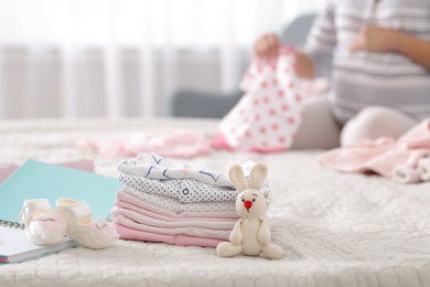 Photo of Baby clothes prepared for maternity hospital and pregnant woman on background