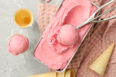 Photo of Delicious ice cream in container and wafer cones on light grey table, flat lay