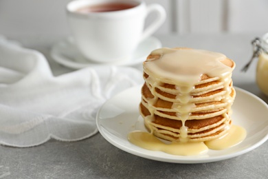 Photo of Plate with pancakes and condensed milk served on table, space for text. Dairy product