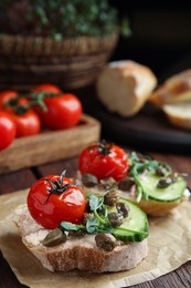 Photo of Tasty bruschettas with vegetables and capers served on wooden table, closeup