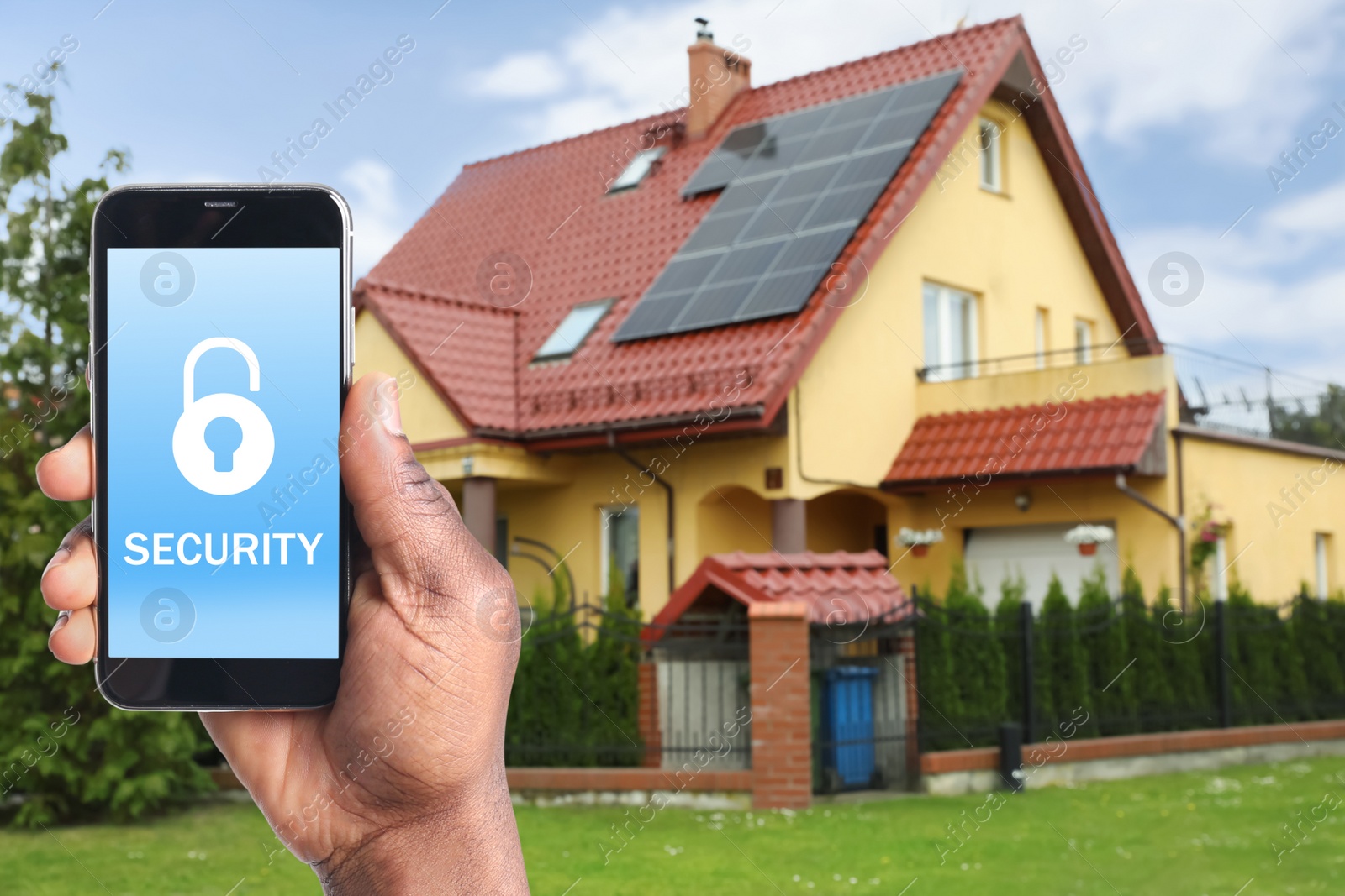 Image of Home security system. African American man with smartphone near his house outdoors, closeup