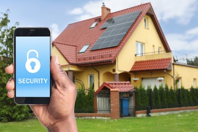 Image of Home security system. African American man with smartphone near his house outdoors, closeup