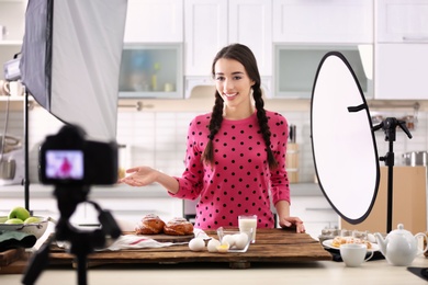Photo of Young food blogger recording video on camera in kitchen