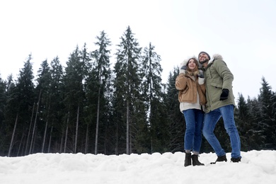 Photo of Couple near conifer forest on snowy day, space for text. Winter vacation