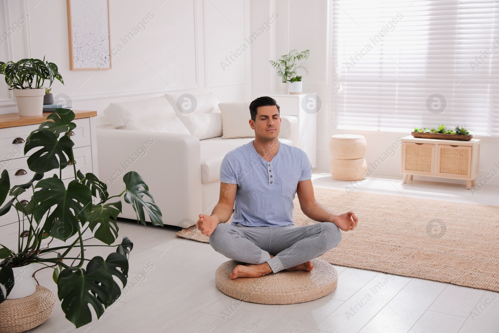 Photo of Man meditating on wicker mat at home