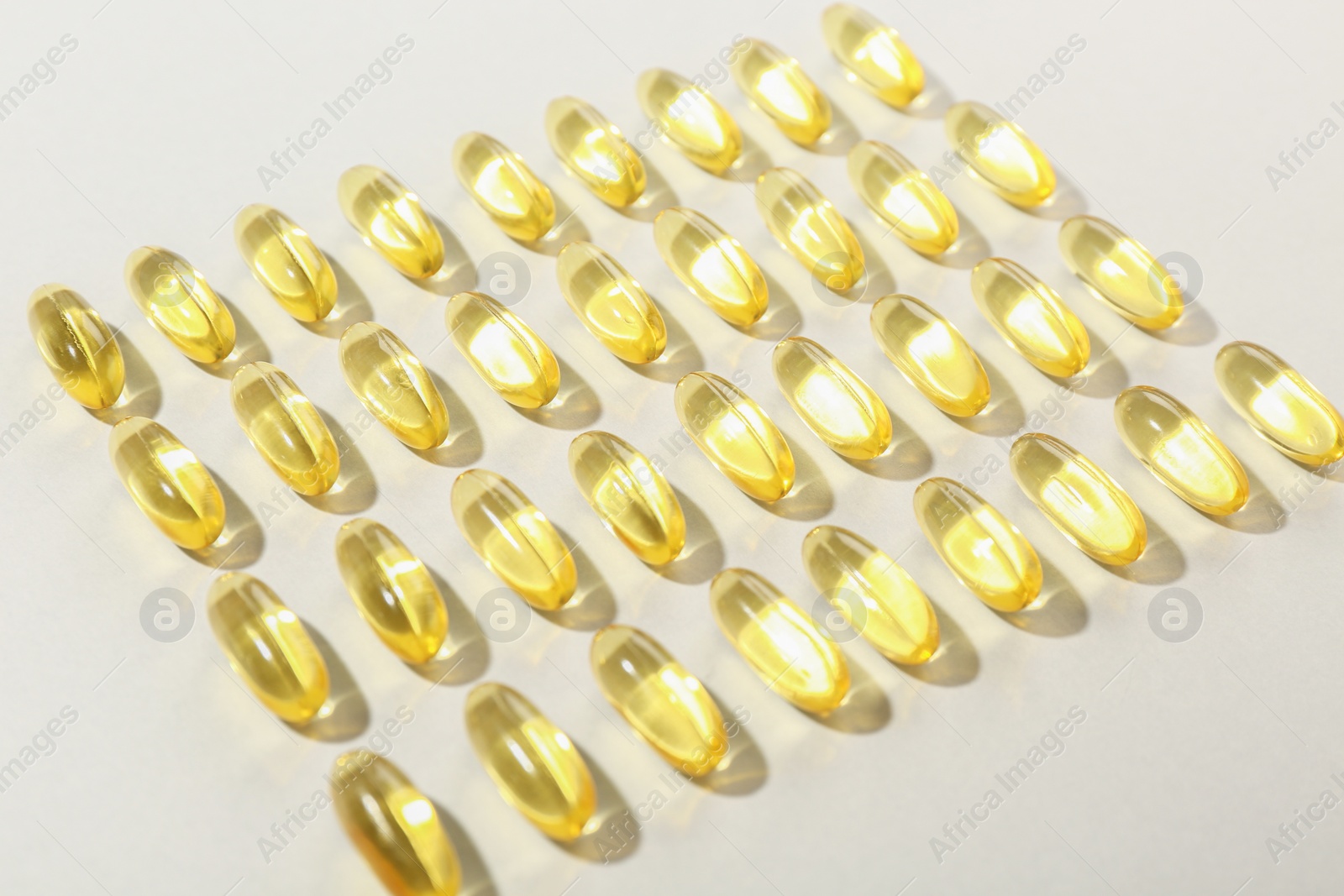 Photo of Many yellow vitamin capsules on light background