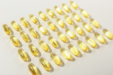 Photo of Many yellow vitamin capsules on light background