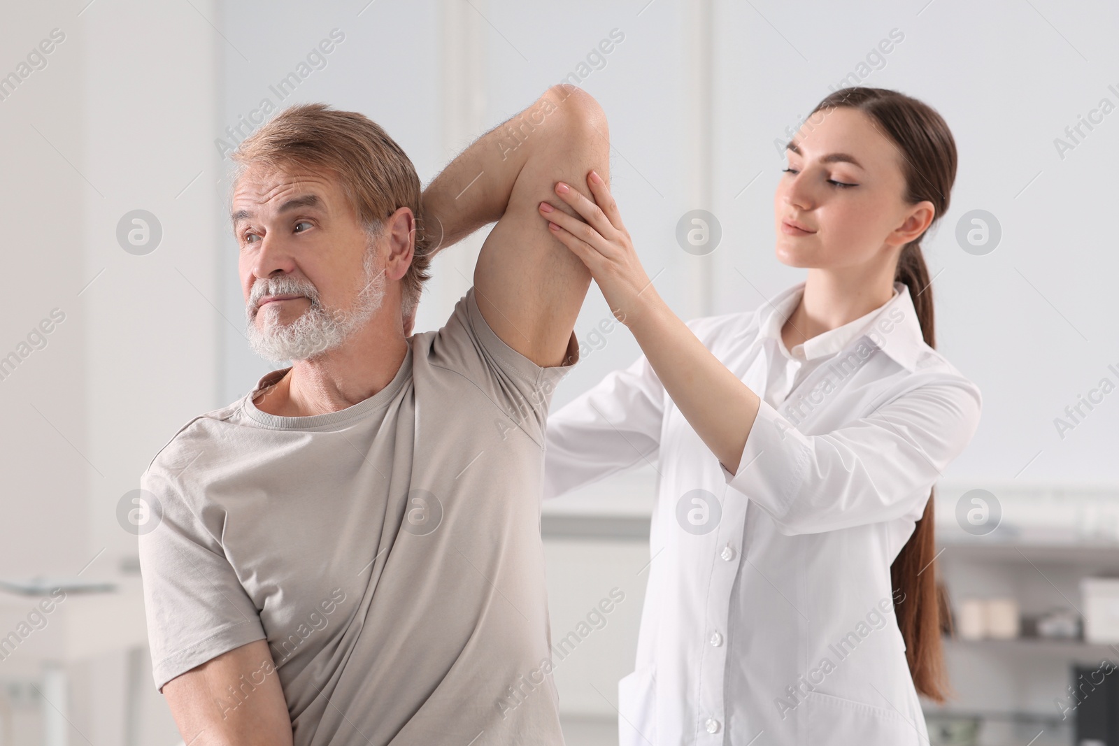 Photo of Professional orthopedist examining patient's shoulder in clinic