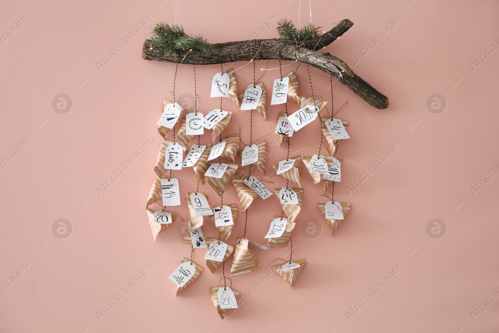 Photo of Christmas advent calendar with small gifts hanging on pink wall