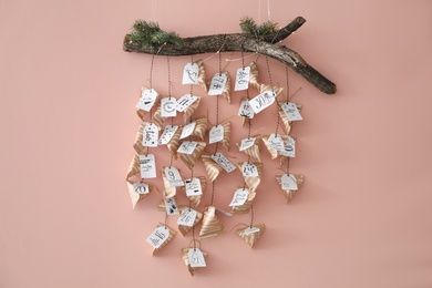 Photo of Christmas advent calendar with small gifts hanging on pink wall