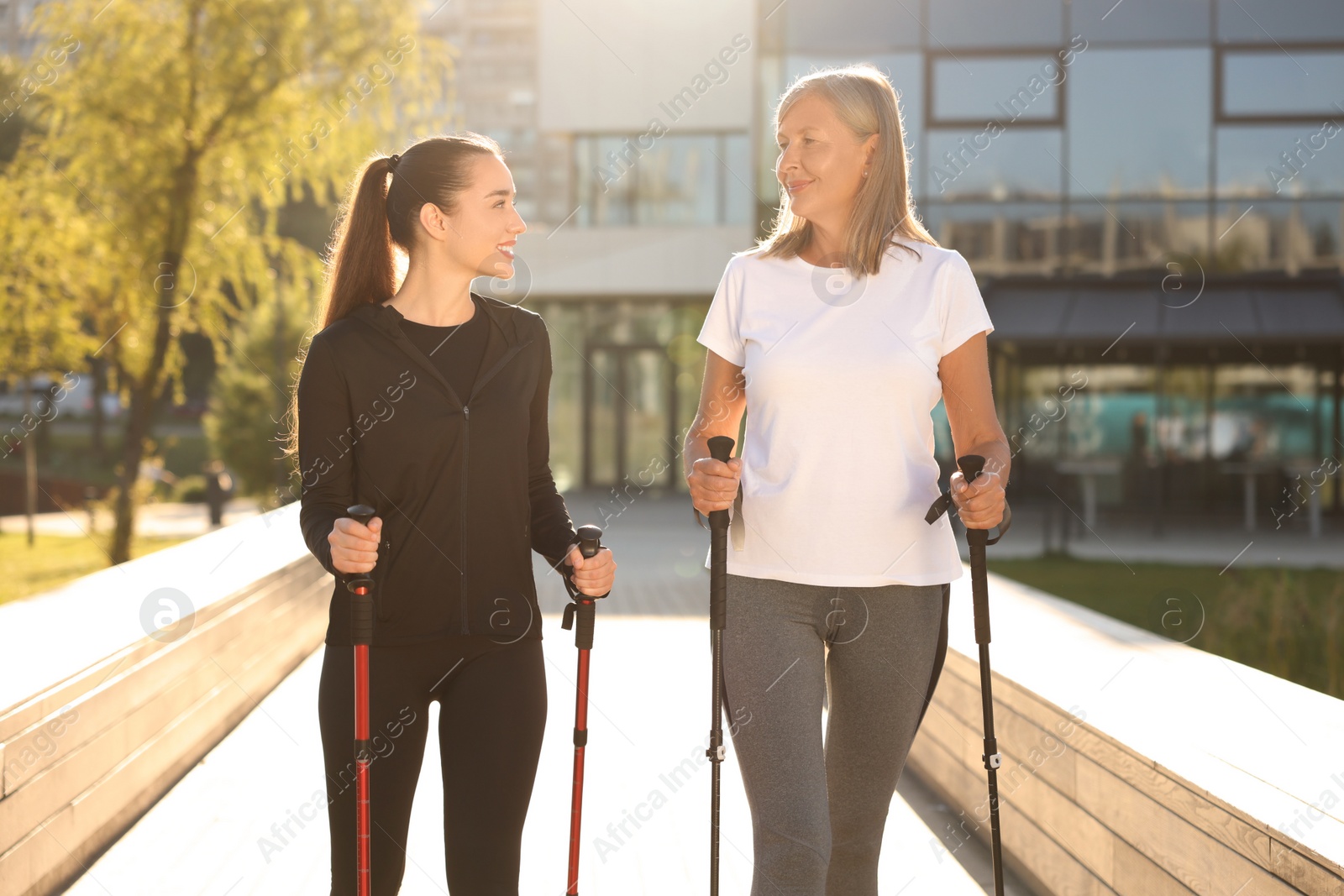 Photo of Happy women practicing Nordic walking with poles outdoors on sunny day