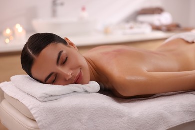 Photo of Woman relaxing on massage couch in spa salon