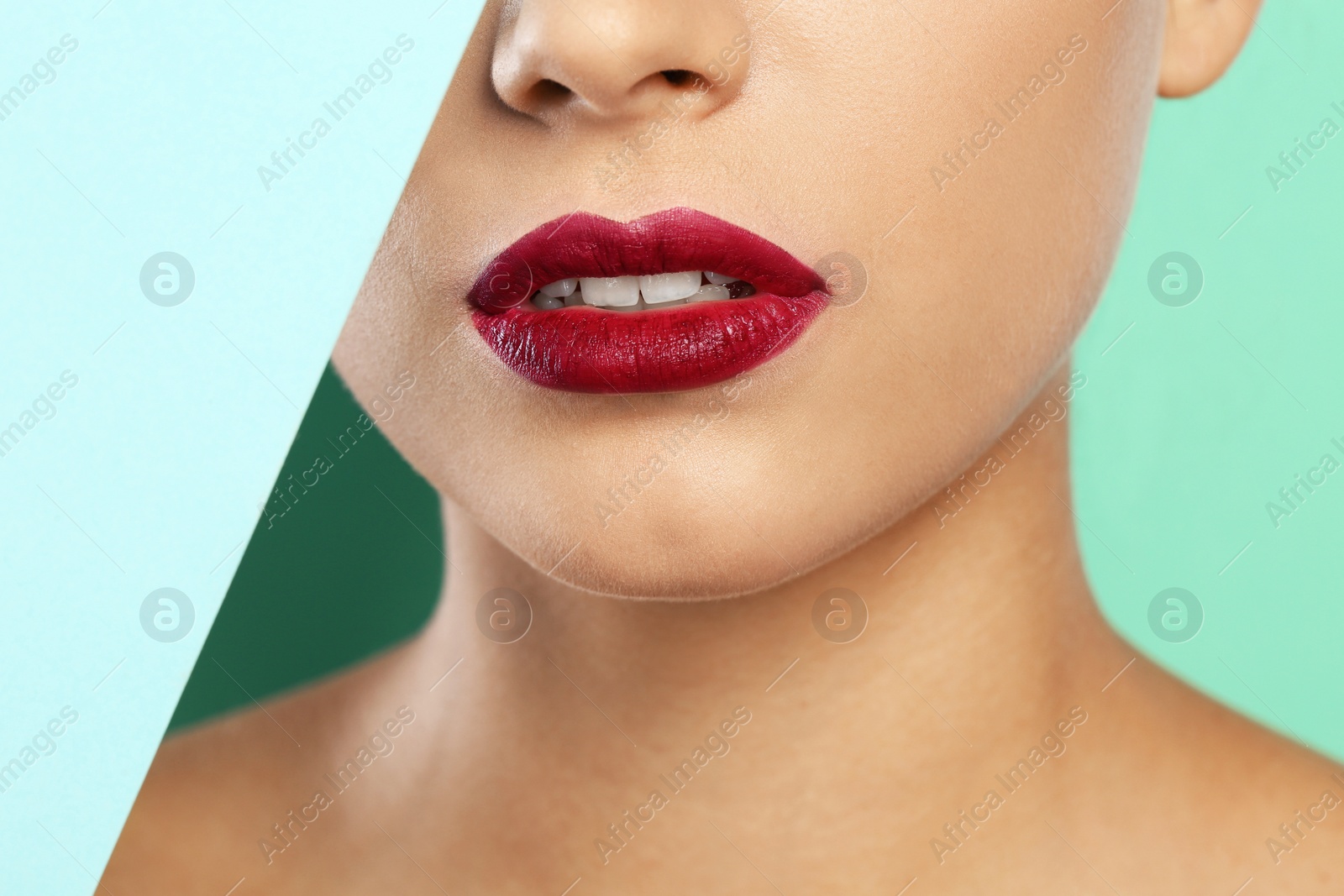 Photo of Young woman wearing beautiful lipstick on color background, closeup