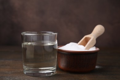 Photo of Vinegar in glass and baking soda on wooden table