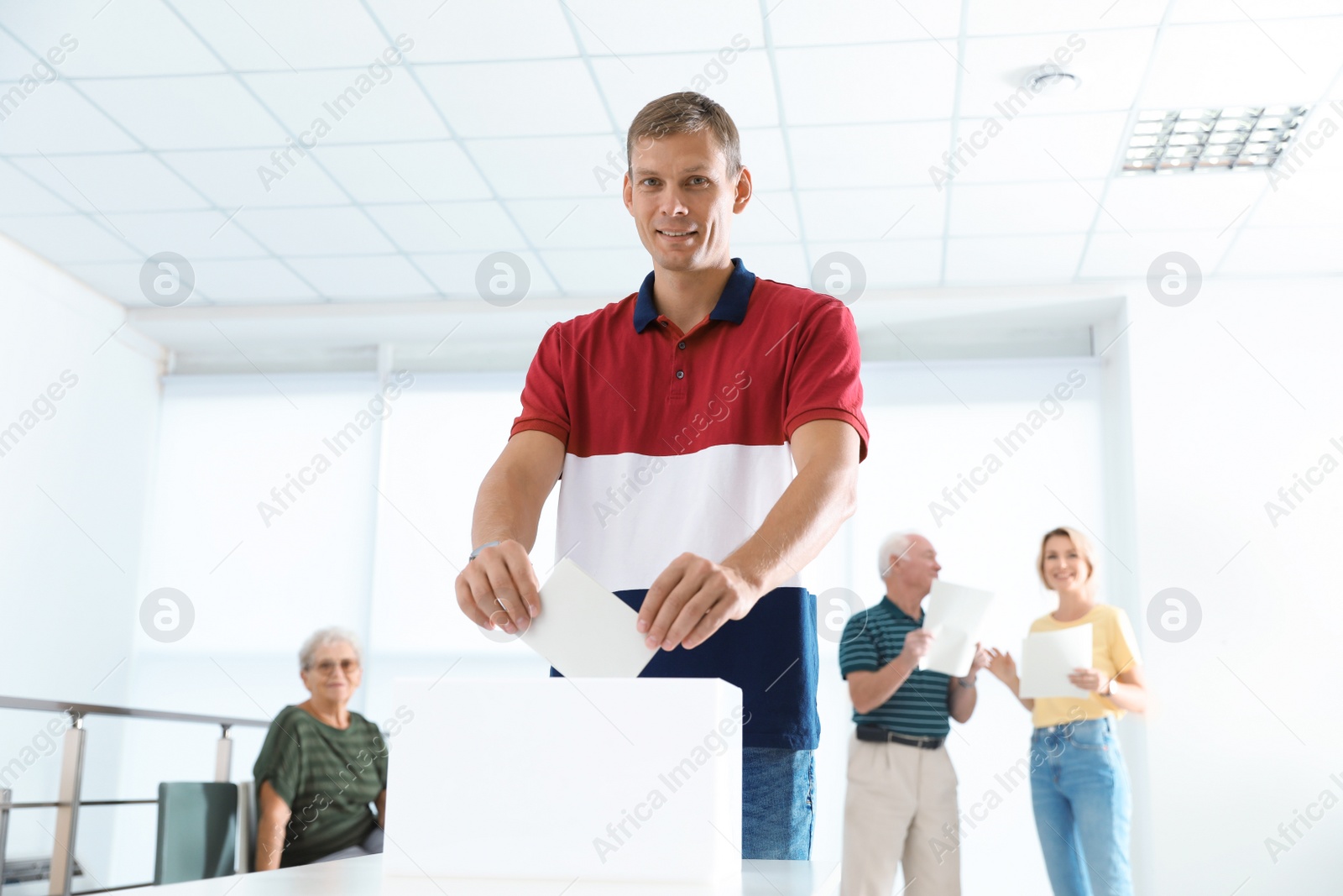 Photo of Man putting ballot paper into box at polling station