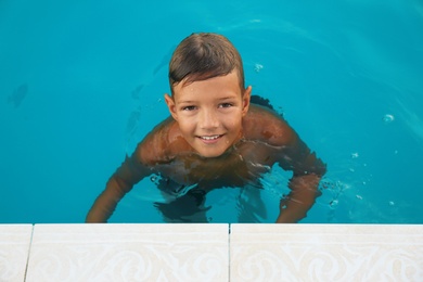 Happy cute boy in swimming pool on sunny day