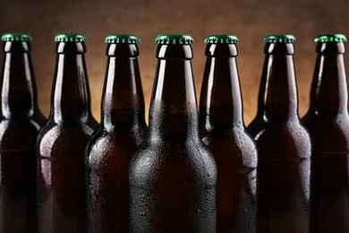 Photo of Many bottles of beer on light brown background, closeup