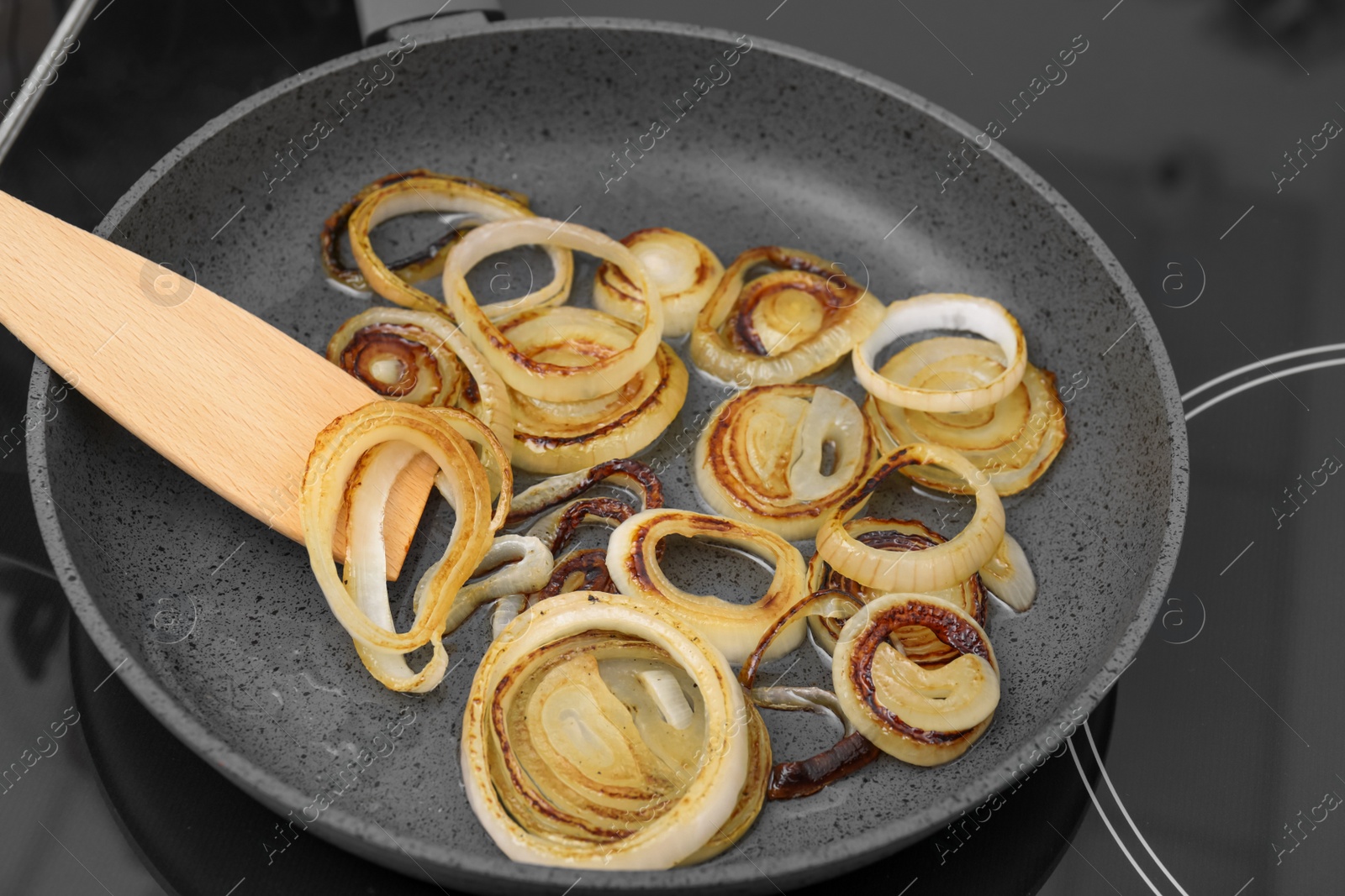 Photo of Cooking onion rings in frying pan, closeup