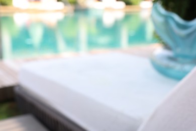 Photo of Sun lounger near outdoor swimming pool, blurred view. Luxury resort