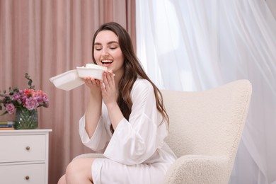 Photo of Beautiful young woman eating her Birthday cake on armchair in room
